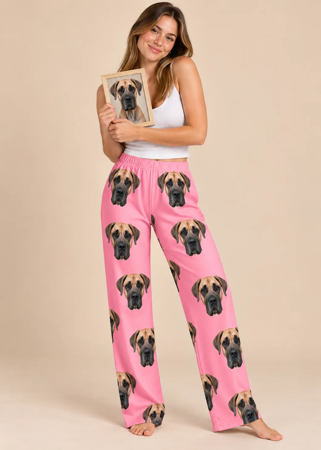 Woman holding a framed great dane portrait in bright pink great dane pajama pants, studio