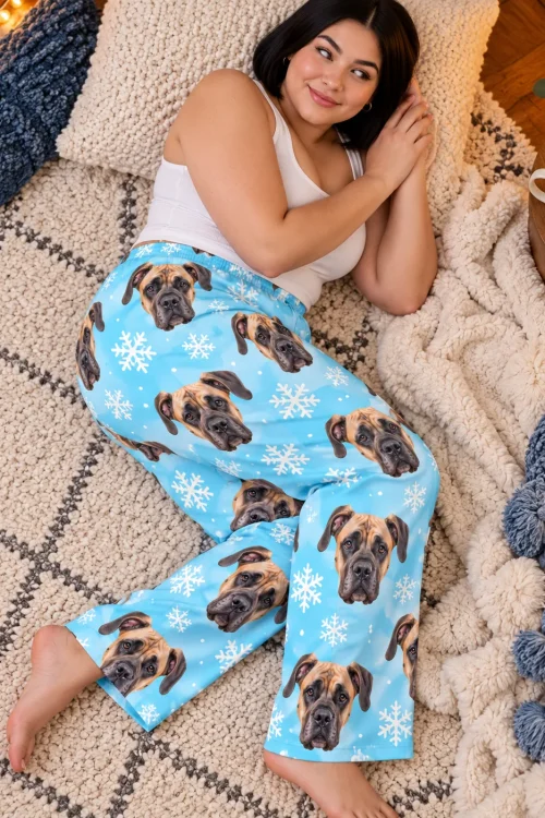 Woman resting on a rug with a hot cocoa beside her in snowflake great dane pajama pants, from above