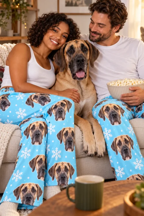 Couple on a sofa with popcorn and a great dane between them, in snowflake great dane pajama pants