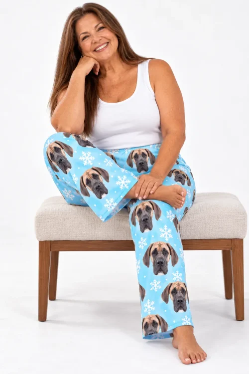 Smiling woman perched on a bench in icy blue snowflake great dane pajama pants