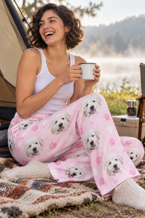 Woman laughing with a tin mug at a lakeside campsite in blush pink paws great pyrenees pajamas