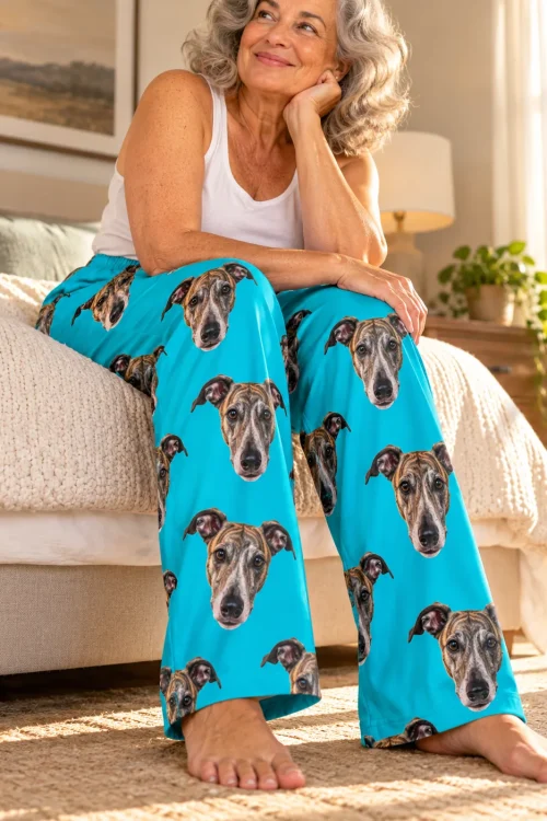 Woman sitting on the edge of a bed, close view of teal greyhound pajamas with dog faces on both legs