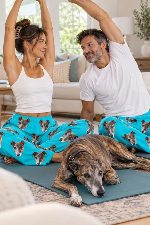Couple stretching on yoga mats in teal greyhound pajamas with a brindle greyhound resting between them