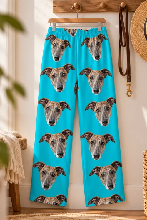 Teal greyhound pajamas hanging on a wooden hanger beside a leash and straw hat, faces printed down both legs