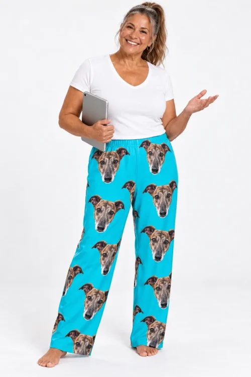 Smiling woman with a tablet in teal greyhound pajamas printed with brindle dog faces, white studio