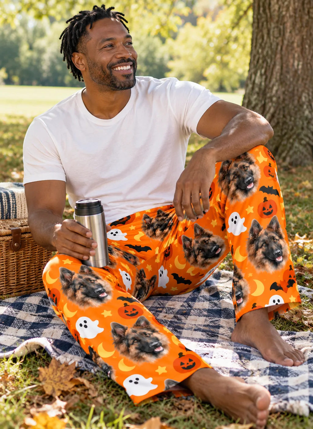 Halloween pajamas: man on a picnic blanket in orange Halloween pajama pants printed with German shepherd faces