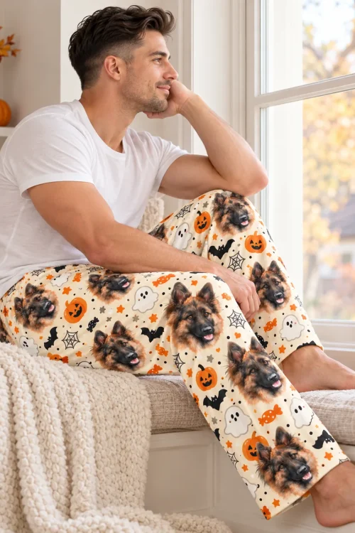 Man on a window seat in cream Halloween PJ pants with German Shepherd faces, ghosts and spiderwebs