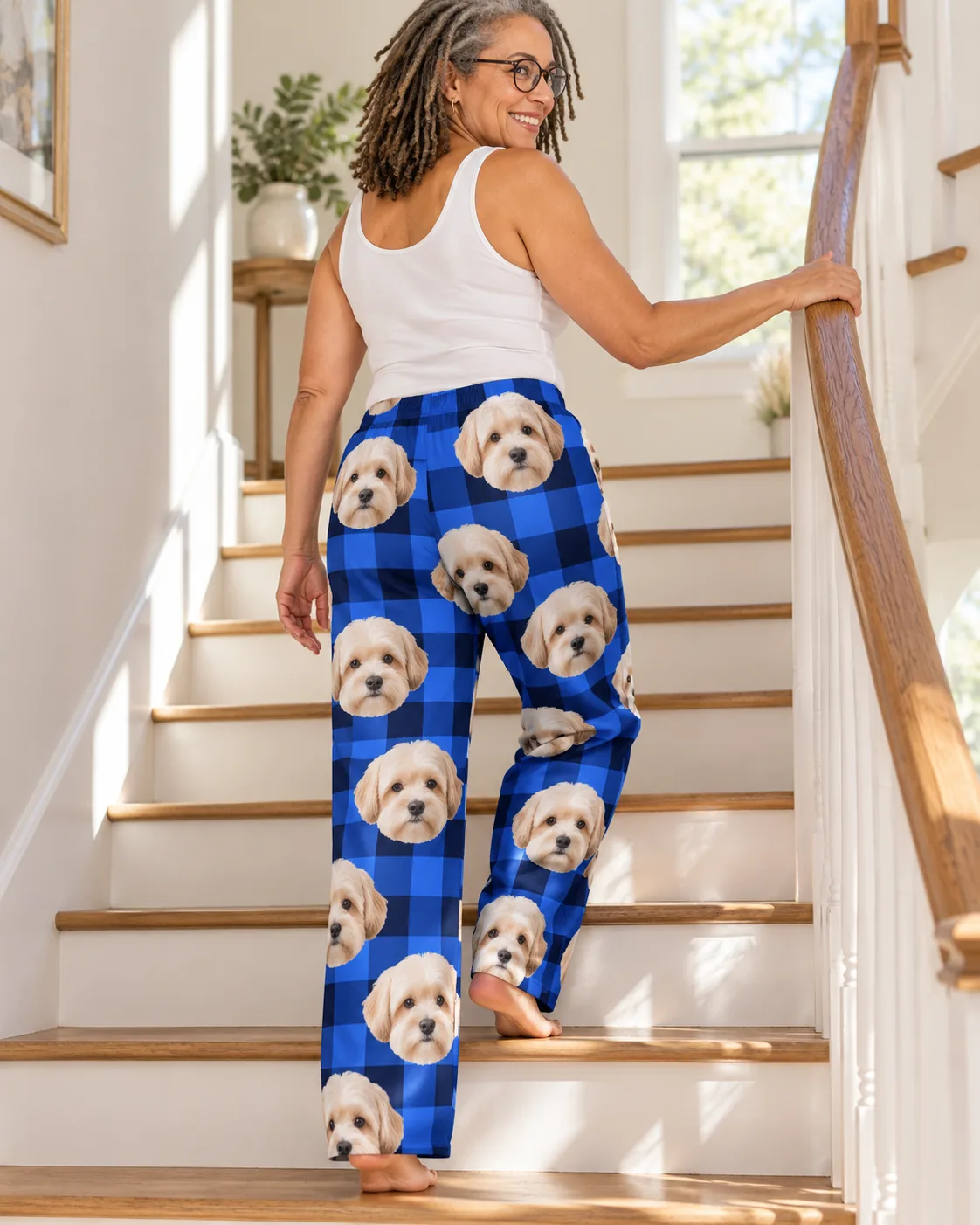 Woman climbing a staircase, back view of blue plaid havanese pajamas with dog faces on both legs
