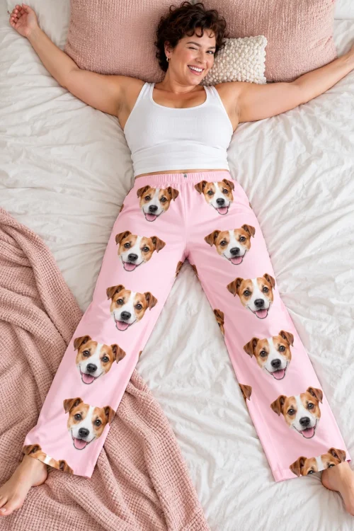 Woman lying on a bed, arms out and winking, in blush pink Jack Russell loungewear with terrier faces