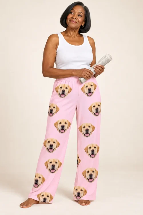 Smiling woman holding a rolled newspaper in blush pink labrador pajama pants, cream studio