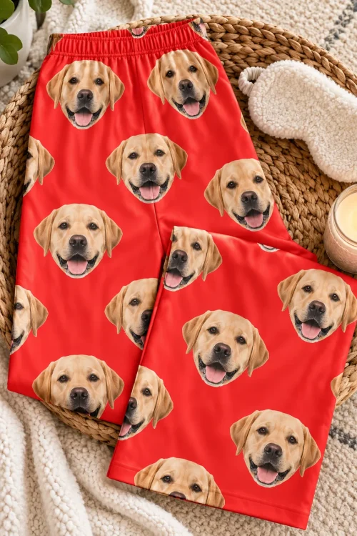 Red labrador pajama pants folded on a woven tray with a sleep mask and a lit candle