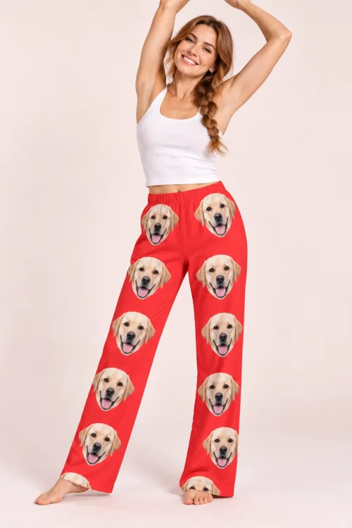 Woman with a long braid stretching her arms up in red labrador pajama pants, pale pink studio