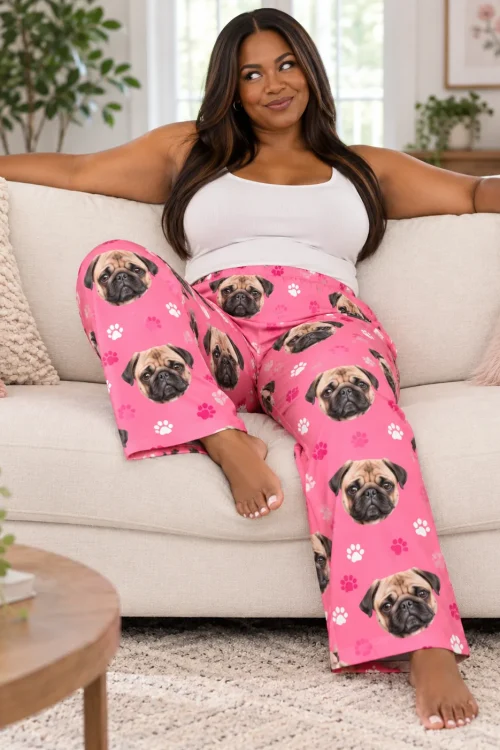 Woman relaxing on a cream sofa in pink paws pajama pants printed with pug faces