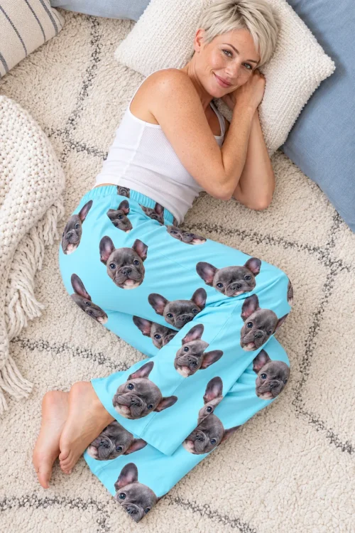 Woman with short blonde hair lying on a rug in light blue pajama pants with French bulldog faces