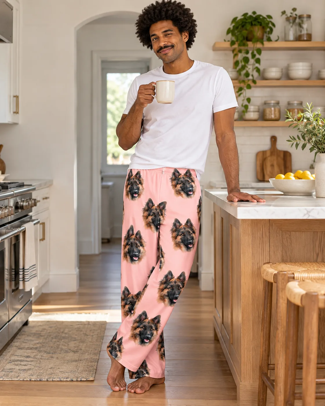 Man with coffee leaning on a kitchen island in light pink pajama pants with German Shepherd faces