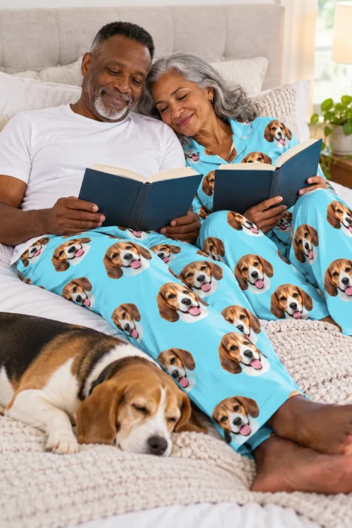 Couple reading in bed in light blue beagle pajamas, their beagle asleep on the blanket beside them