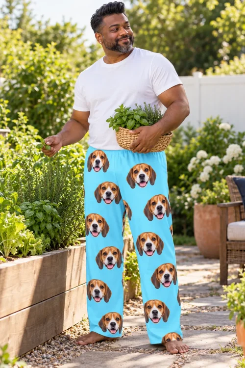 Man picking herbs in a backyard garden in light blue beagle pajama pants printed with beagle faces