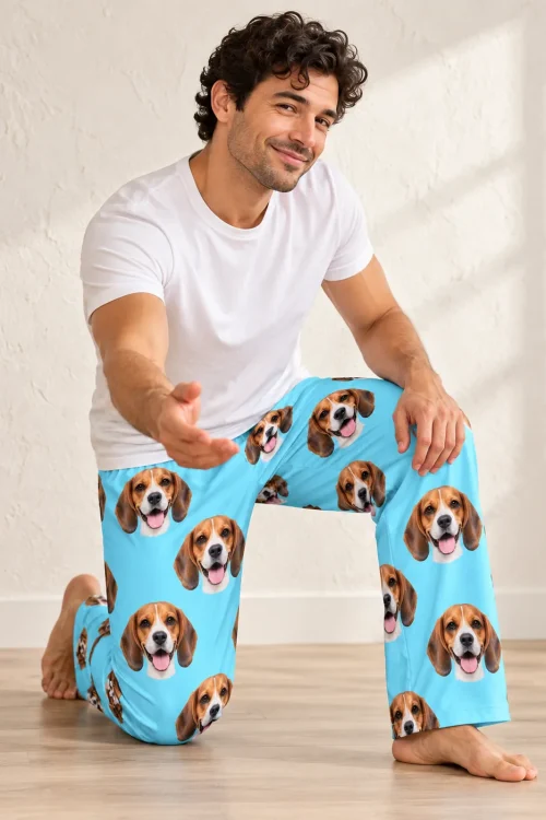Man kneeling with a hand outstretched, in light blue mens beagle pajamas against a textured cream wall
