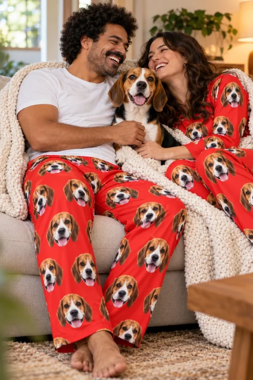 Couple under a cream knit blanket on the sofa with their beagle, both in red beagle pajamas