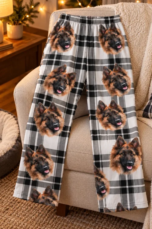 Black and white plaid pajama pants with German Shepherd faces draped over an armchair by a dog bed