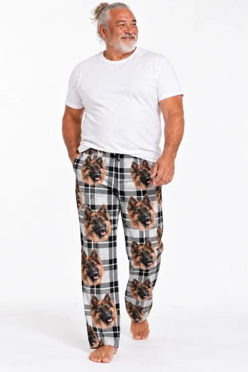Smiling man in black and white plaid pajama pants with German Shepherd faces on a white studio backdrop