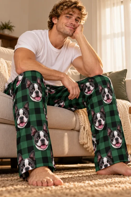 Curly-haired man resting his chin on his hand on a sunny sofa, in green plaid Boston terrier pajama pants