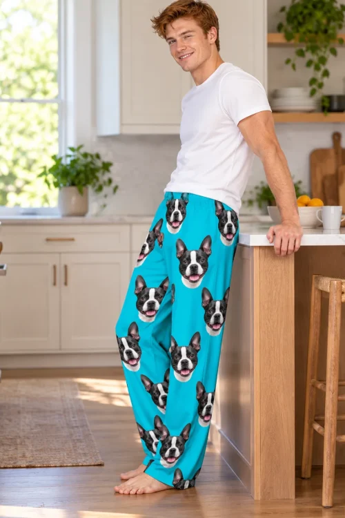 Red-haired man leaning on a kitchen island in teal Boston terrier pajama pants with faces down both legs