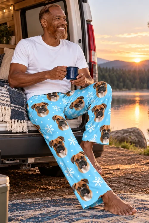 Man with a mug on a camper van tailgate at a lake sunrise in snowflake boxer dog pajamas