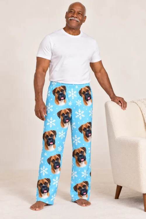 Older man with a mustache standing by a cream armchair in snowflake mens boxer dog pajamas