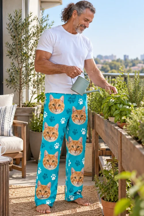 Man watering herbs on a sunny balcony in teal paws cat pajama pants