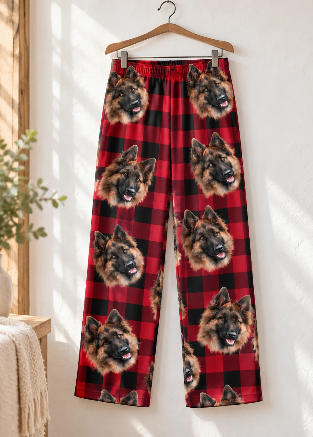 Men's Christmas pajamas: red plaid pajama pants printed with German shepherd faces on a wooden hanger
