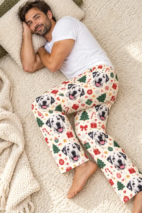 Man lying on a cream rug with a pillow in Christmas cream dalmatian pajama pants, seen from above