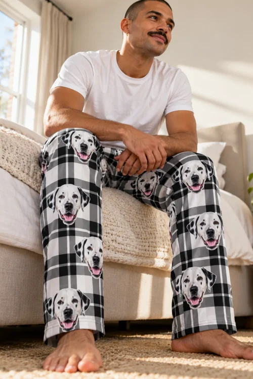 Man sitting on the edge of his bed in white plaid mens dalmatian pajamas covered in dalmatian faces