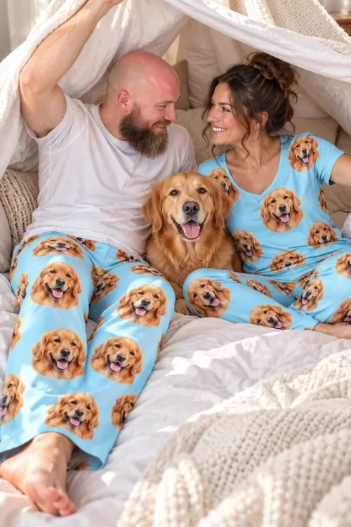 Couple in a blanket fort with their golden retriever, his light blue pants printed with golden faces
