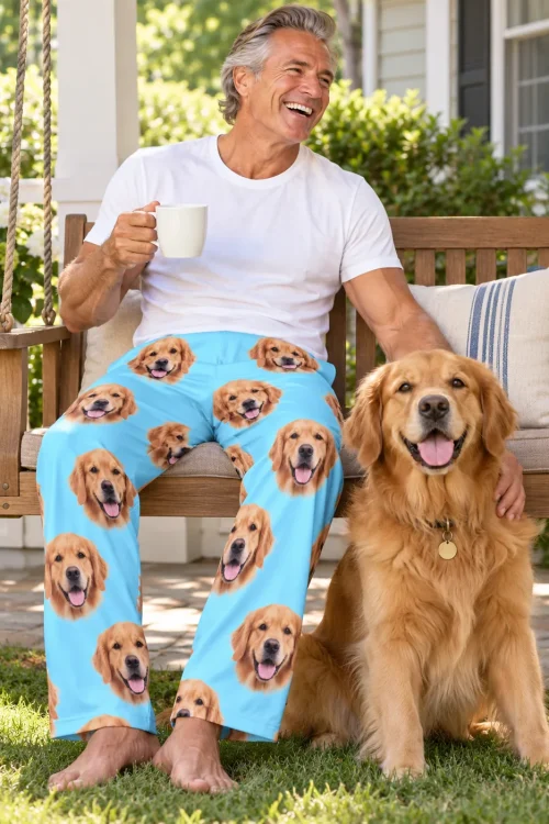 Gray-haired man with coffee on a porch swing in light blue golden retriever pajama pants beside his golden