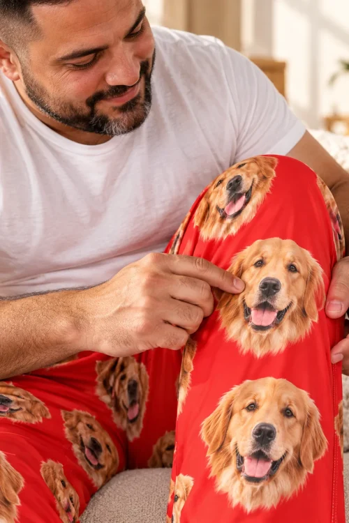 Man on a sofa pointing at a golden face on his red men's golden retriever pajama pants