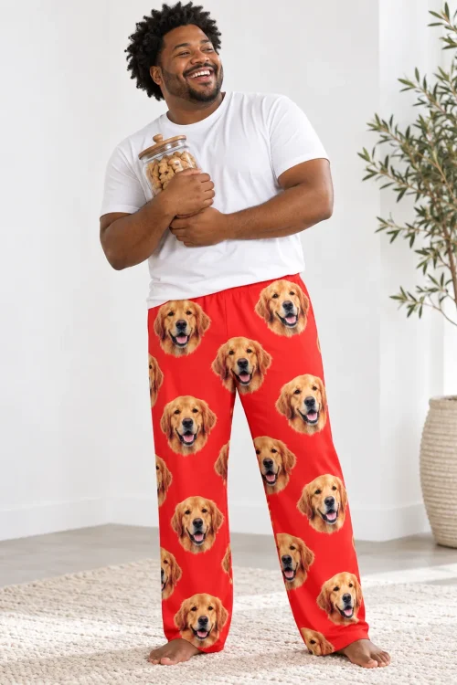 Laughing man hugging a jar of dog treats in red men's golden retriever pajama pants, white studio