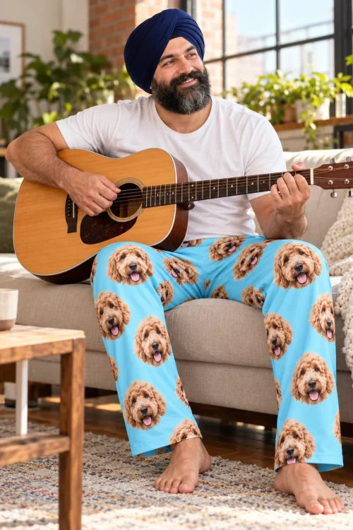 Man in a navy turban playing guitar on the sofa in light blue goldendoodle pajama pants