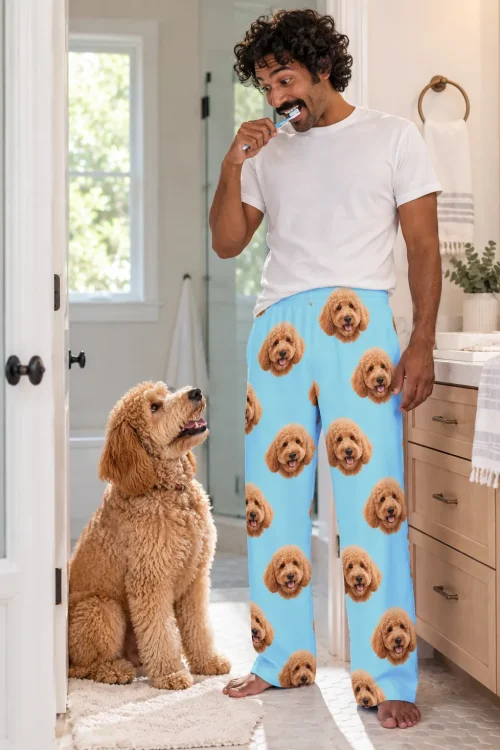 Man brushing his teeth in light blue goldendoodle pajama pants while his doodle watches from the doorway
