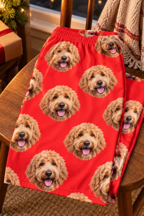 Red goldendoodle pajama pants with an elastic waistband draped over a wooden chair beside a wrapped gift