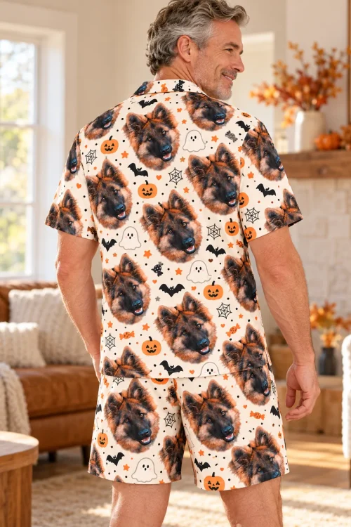 Back view of a man in cream Halloween pajamas with German shepherd faces, ghosts and webs in a fall living room