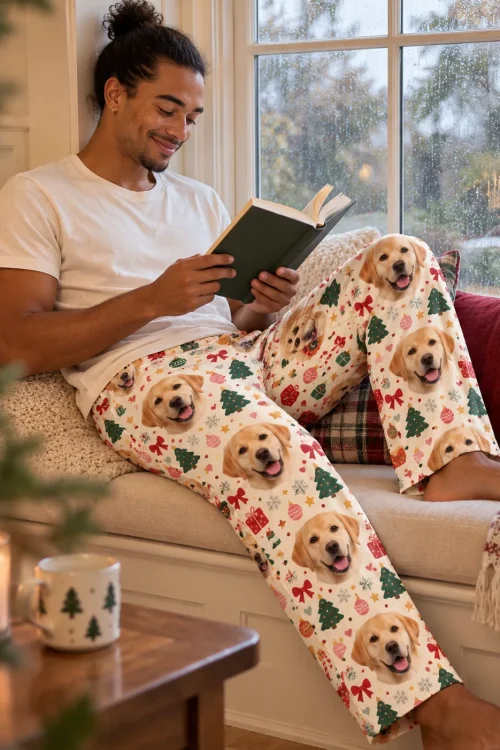 Man reading in a window nook in Christmas cream labrador pajama pants with trees and candy canes