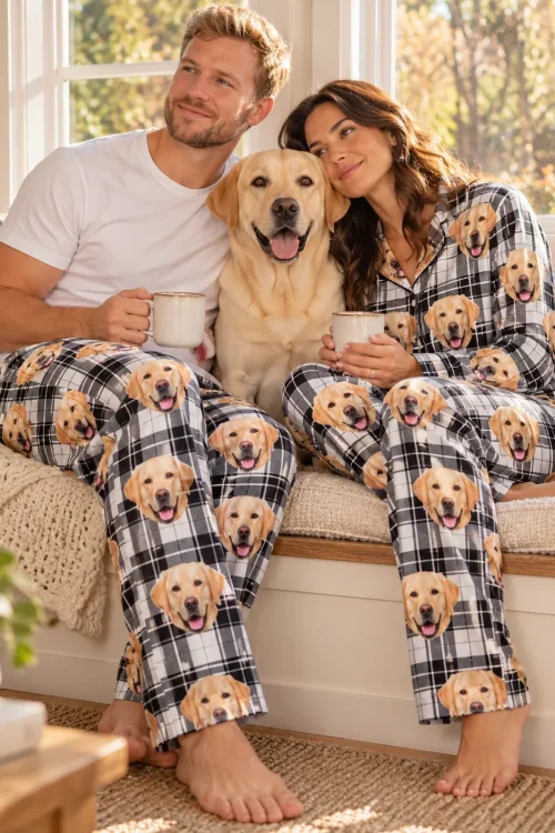 Couple with mugs on a window seat, their yellow lab between them, in white plaid labrador pajamas
