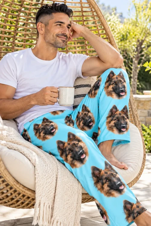 Man in a wicker hanging chair on a sunny patio in light blue pajama pants with German Shepherd faces
