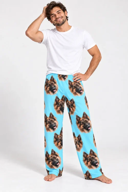 Smiling man in a white tee and light blue pajama pants covered in German Shepherd faces