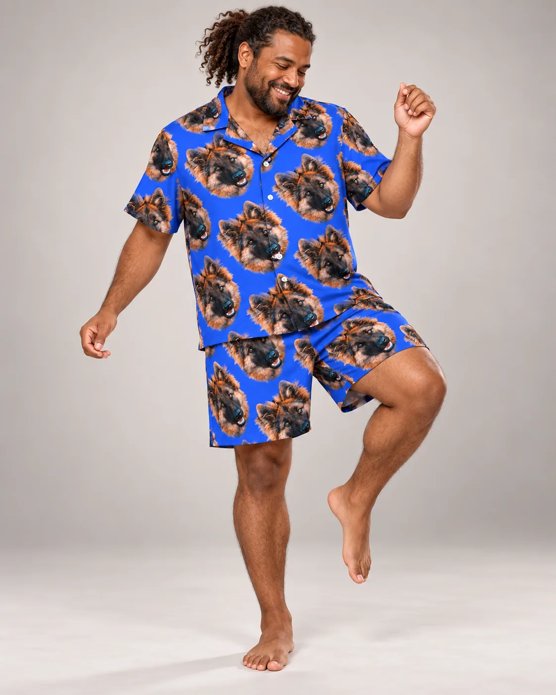 Man dancing barefoot in a royal blue pajama set printed with German shepherd faces