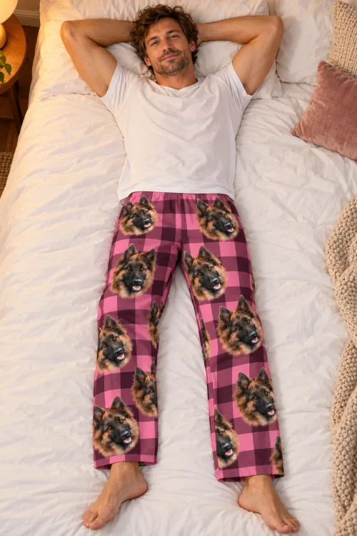 Man lying on a white bed in pink plaid pajama pants printed with German Shepherd faces