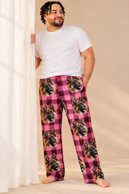 Man by a sheer curtain in pink plaid pajama pants with German Shepherd faces on a warm beige backdrop