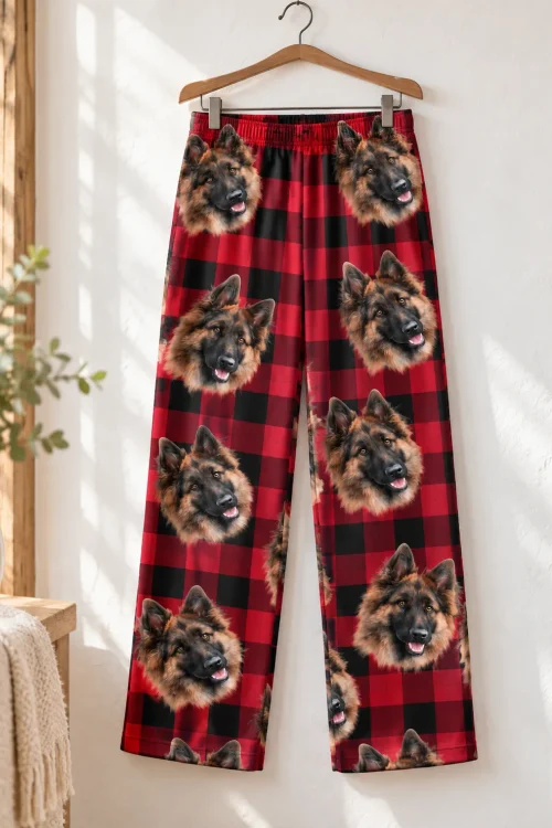 Red plaid pajama pants with German Shepherd faces on a wooden hanger against a white wall