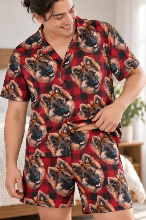 Man adjusting his red and black plaid pajama shirt with German shepherd faces in a bright bedroom